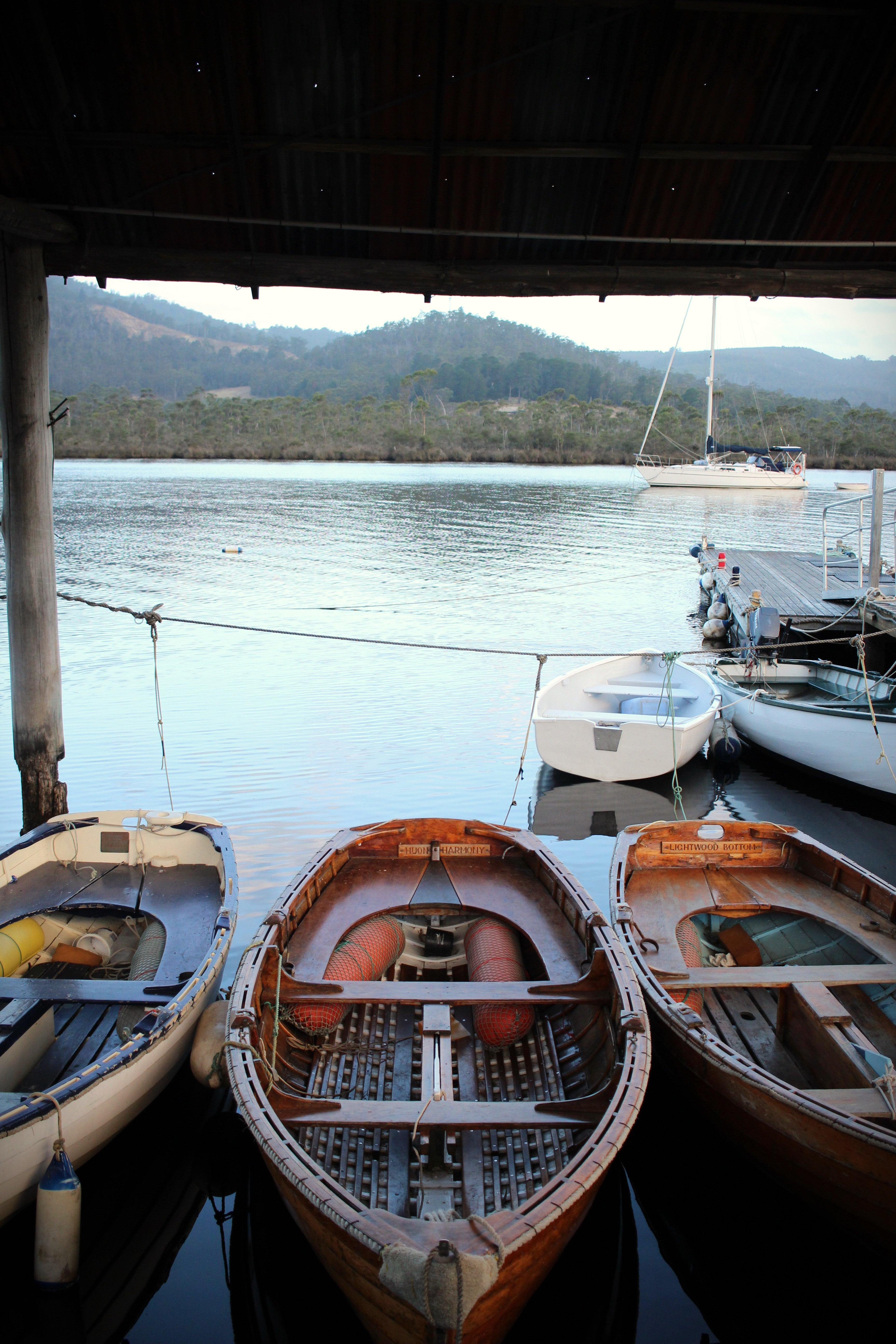 Three boats docked at a pier with mountains in the background